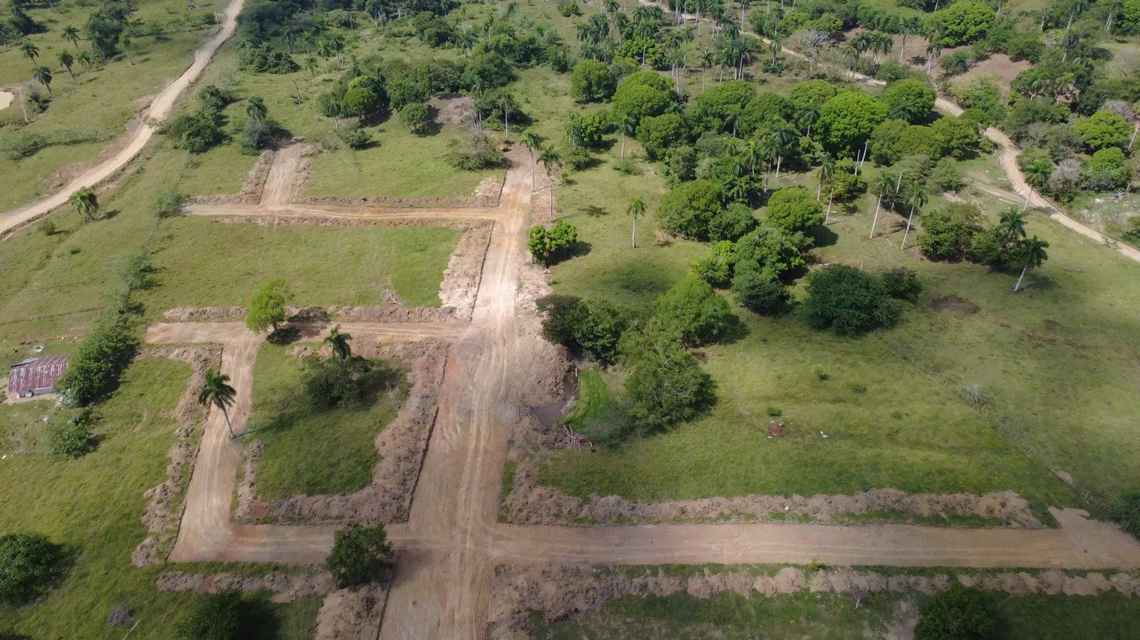 Vista aérea real del terreno con vías y lotes en proceso de conformación.